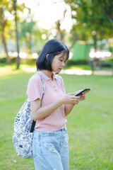 A young woman listens to music on her phone. An Asian woman stretches after sitting for a long time.