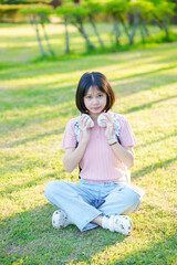 Fototapeta premium A young woman listens to music on her phone. An Asian woman stretches after sitting for a long time.
