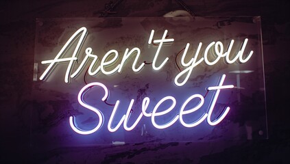 A neon sign displaying the phrase 'Aren't you sweet', ideal for a playful atmosphere, light-hearted theme