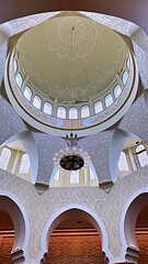 Beautiful interior of a mosque dome featuring Arabic calligraphy, ornamental details, and an elegant chandelier. A masterpiece of Islamic architecture and spiritual beauty.
