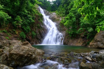 Fototapeta premium Majestic waterfall surrounded by lush greenery in a tropical forest setting