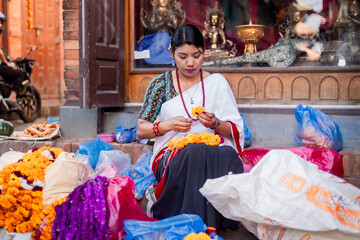 Newari Girl in traditional attire Crafting Globe Amaranth Garlands(makhmali flower) for Bhai Tika in tihar