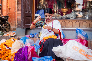 Newari Girl in traditional attire Crafting Globe Amaranth Garlands(makhmali flower) for Bhai Tika in tihar
