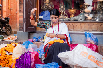 Newari Girl in traditional attire Crafting Globe Amaranth Garlands(makhmali flower) for Bhai Tika in tihar