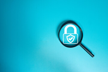 Cybersecurity concept. Magnifying glass focusing on a secure padlock icon, symbolizing a security audit, data protection, and privacy verification on a blue background with copyspace.