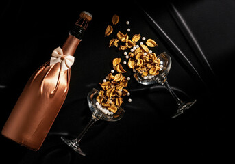 Rose Gold Champagne Bottle with Bow and Glasses of Golden Snacks on Black Background