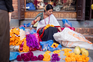 Newari Girl in traditional attire Crafting Globe Amaranth Garlands(makhmali flower) for Bhai Tika in tihar