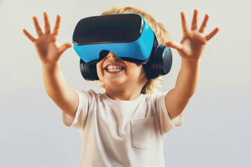 A boy wearing a blue and black virtual reality headset appears excited and smiles widely. He raises both hands to interact with the virtual world against a plain background.