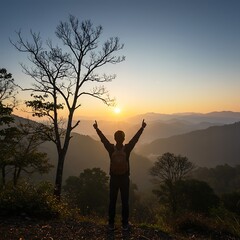 Man with arms raised in triumph at sunrise over mountains.