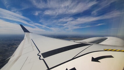 Obraz premium View from Airplane Window with Wing and Blue Sky