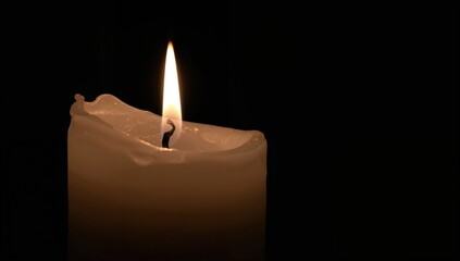 A large white candle lit against a dark backdrop, symbolizing solitude and tranquility