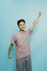 Teen celebrates success with fist pump against a vibrant blue backdrop, radiating youthfulness and positive energy perfect for motivational concepts
