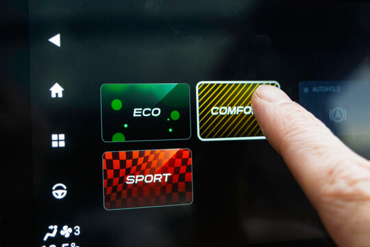 Finger taps car touchscreen driving mode menu showing ECO COMFORT SPORT, offering choice between efficiency, comfort and sport.