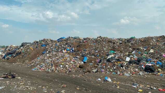 A large garbage dump stretches alongside the river, highlighting environmental risks associated with petroleum waste, Earth Day - Powered by Adobe