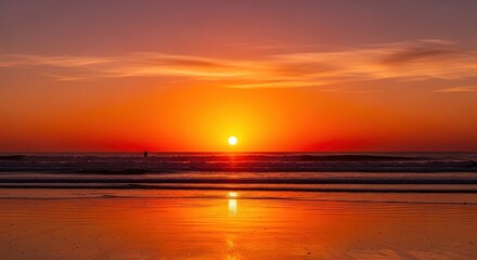 Vivid sunset over the ocean reflecting on the wet sand, horizon line view