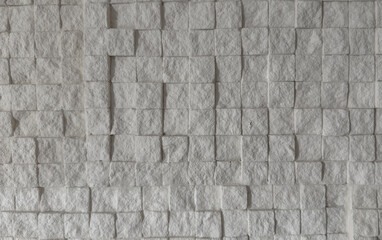 Close-up of white stone wall made of square tiles showing geometric 3D texture