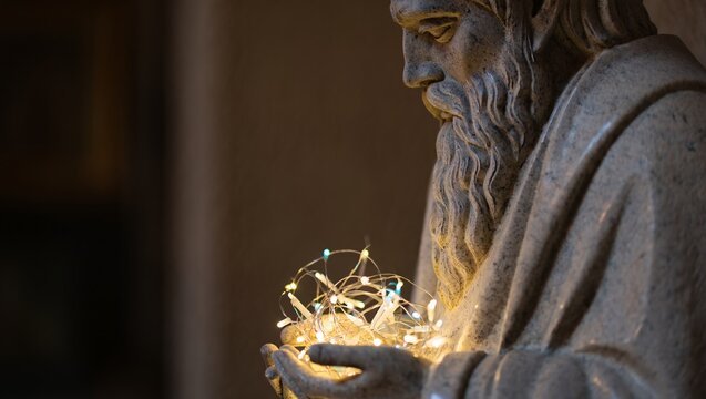 Ancient stone statue illuminated by warm fairy lights in a dimly lit space