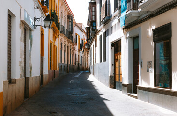 Cobblestone street winding through the old town of Cordoba, Spain, featuring traditional Spanish architecture, historic buildings with colorful balconies, and sunlight casting long shadows