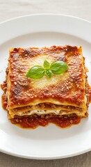 Delicious Lasagna Bolognese with Fresh Basil Garnish on a White Plate.