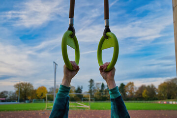 Hands holding gymnastic rings outdoor training, fitness exercise and strength workout concept, healthy lifestyle and motivation at sports park