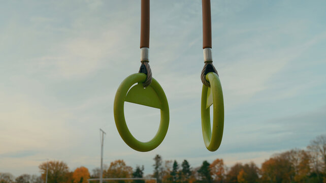 Outdoor gymnastic rings workout equipment, fitness training bars at sports park, healthy active lifestyle exercise concept, modern outdoor fitness structure