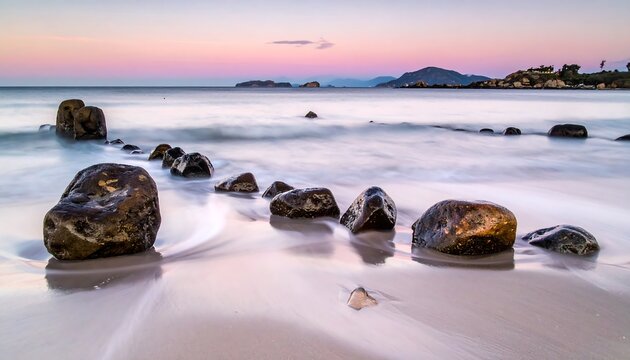 Serene coastal scene. Smooth water flows over sand towards a rocky barrier and islands under a pastel sky at dawn or dusk - Powered by Adobe