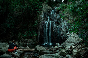 Traveler admiring a waterfall in the heart of the forest