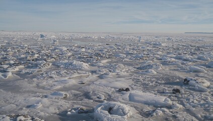 Frozen sea ice and snow-covered stones along the horizon, seasonal change