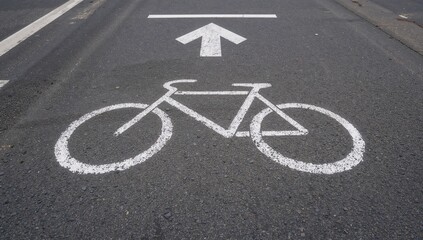 Obraz premium The road sign indicating a bike path, marked with white paint on asphalt, emphasizes safe travel for cyclists