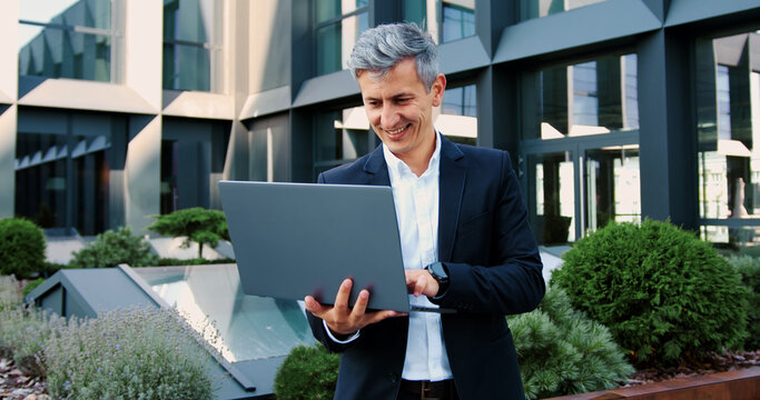 Business owner company CEO busy with online project startup analyze data. Mature successful businessman working, scrolling, typing on laptop