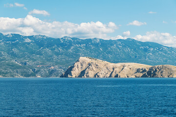 Rocky coastal landscape with mountains and blue sea under a clear sky