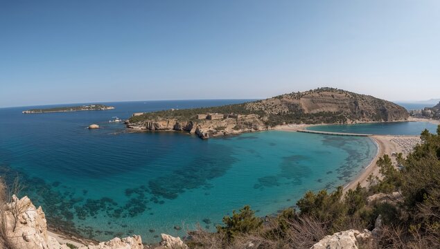 Panoramic shot of a sandy beach with crystal-clear waters and a coastal fortress in the background, a popular spot in the Dodecanese region.