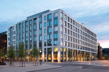 Modern office building stands tall in a bustling urban setting during twilight, showcasing sleek design and reflective glass windows