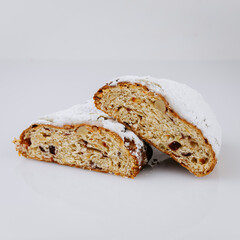 Sliced Christmas stollen with nuts and dried fruits on white background, festive dessert
