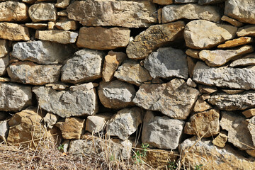 Fototapeta premium Natural stone wall as a fence in a field