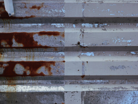 A compelling, high-resolution photograph capturing the textured surface of old, corrugated metal. The horizontal ridges of the metal create a linear pattern, emphasizing the grungy and industrial
