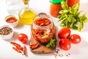 Dried organic tomatoes preservation with herbs and olive oil in jar.	