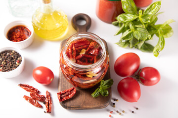 Dried organic tomatoes preservation with herbs and olive oil in jar.	