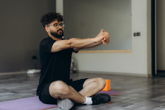 Man stretching arms doing yoga on mat - Powered by Adobe