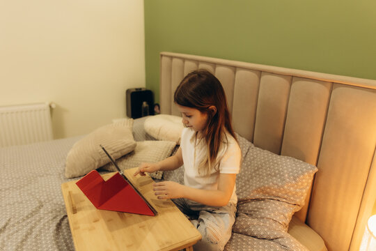 Young Girl Using a Tablet While Sitting on a Bed