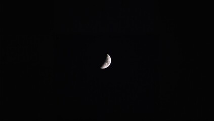 The Moon illuminated in its early first quarter phase, showcasing its crescent shape, celestial observation