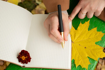 A woman's hand writes in a notebook with a pen