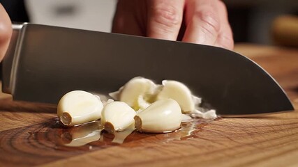 Garlic cloves being crushed gently, slow motion, cooking sounds.