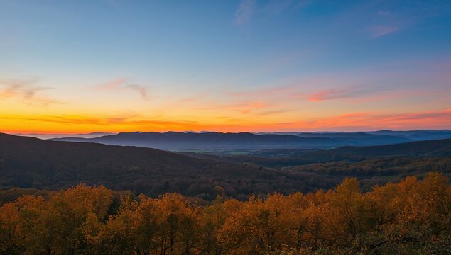 A beautiful sunset illuminating hills and valleys adorned with golden autumn foliage, showcasing seasonal change
