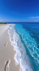 Sunlit Tropical Beach Shoreline with Gentle Waves and Footprints on White Pebbles Under a Clear Blue Sky