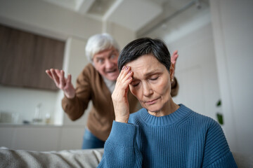 Fototapeta premium Depressed exhausted wife enduring cruel jokes and screams from hysterical husband in silent suffer. Marital breakdown after years of abuse, manipulation. Toxic relations.