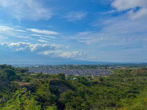Discover stunning coastal city views with lush green hills under a bright blue sky today