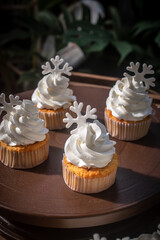 White buttercream cake decorated with snowflake toppers in a cozy Christmas and Happy New Year still life setting. The festive cake is placed on a rustic wooden table with warm light.