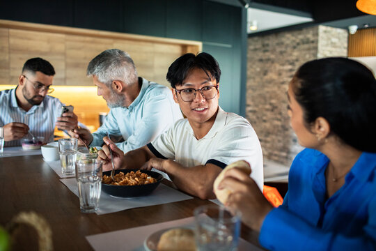 Young adult man chatting with coworkers during relaxed office lunch - Powered by Adobe