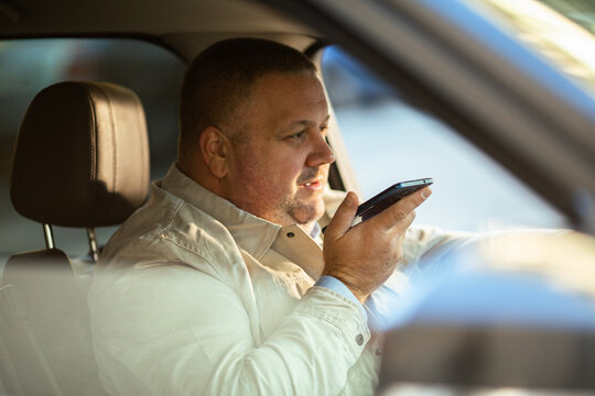 Adult man focused using smartphone voice command in car - Powered by Adobe